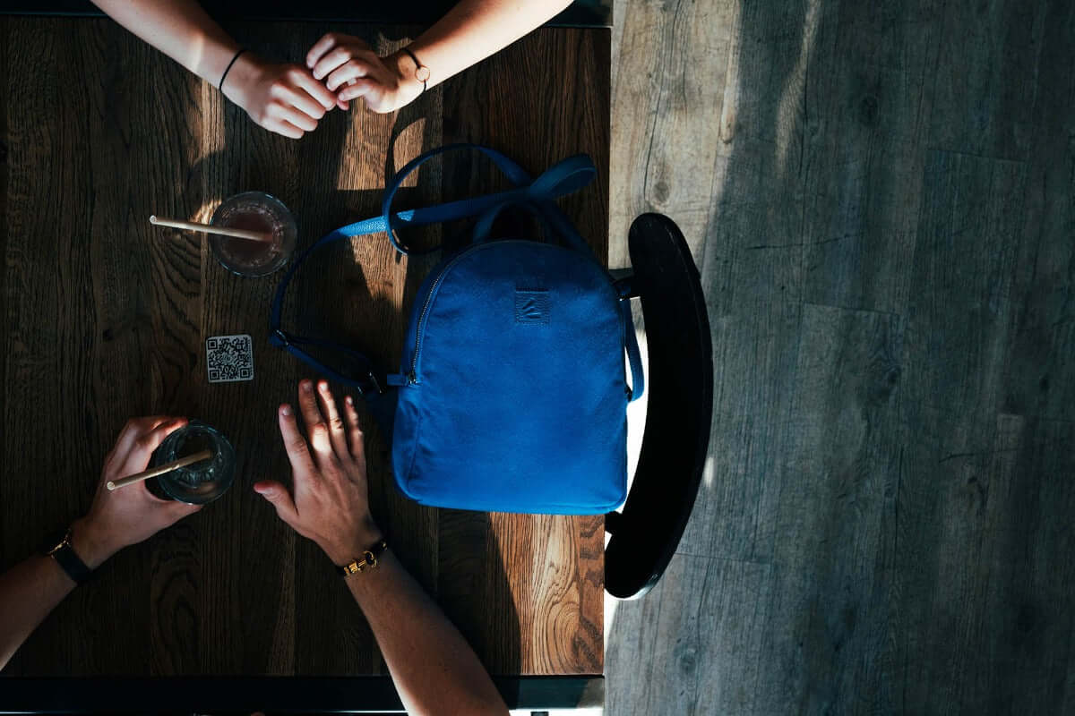sac à dos SLP en velours de laine bleue sur une table avec des mains et des boissons