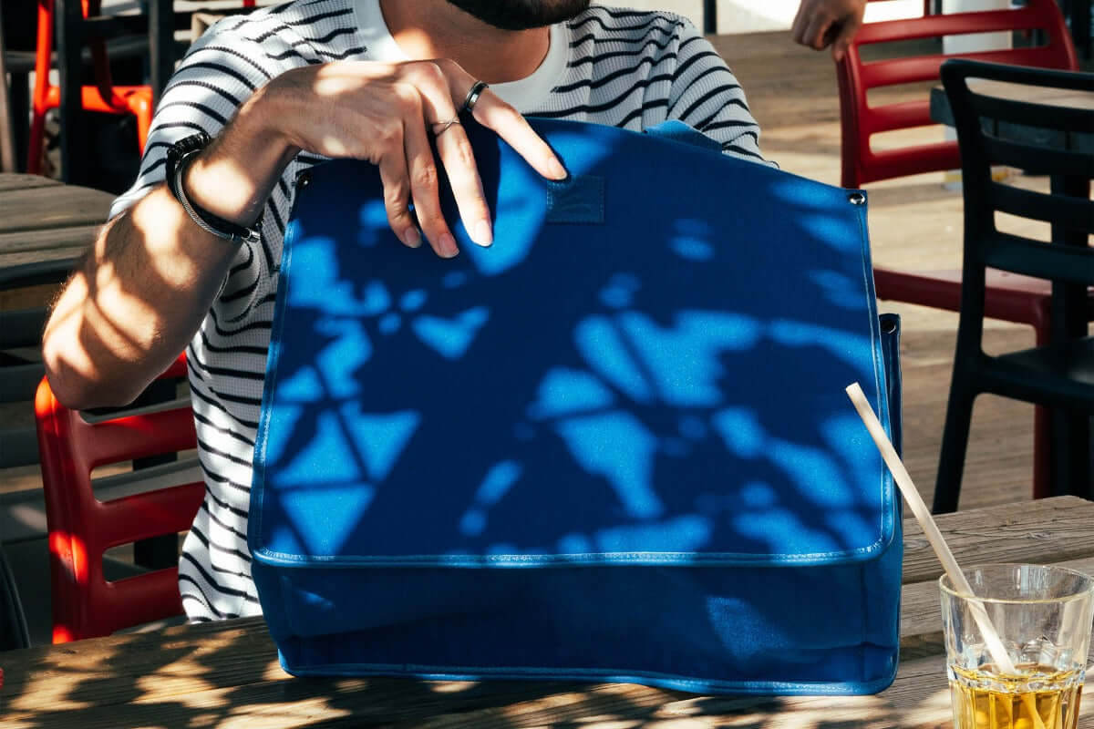 Personne tenant le Grand cabas SLP bleu avec des ombres sur la table.